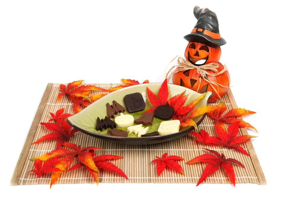 Halloween-themed chocolates, decorative pumpkins, and colorful autumn leaves arranged on a traditional Japanese-style tray.