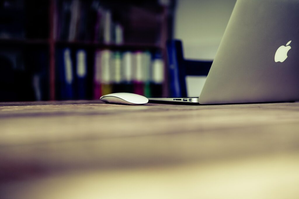 A laptop and computer mouse on a desk, representing online resume editing and professional translation services.