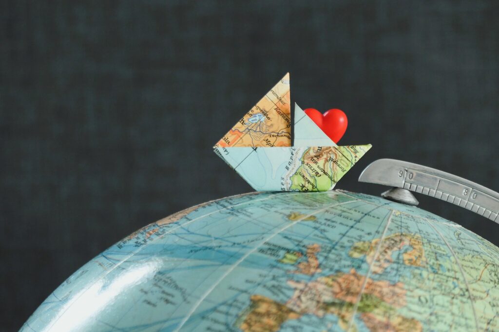 Globe with a paper boat and heart, representing international residents, immigration, and living abroad.