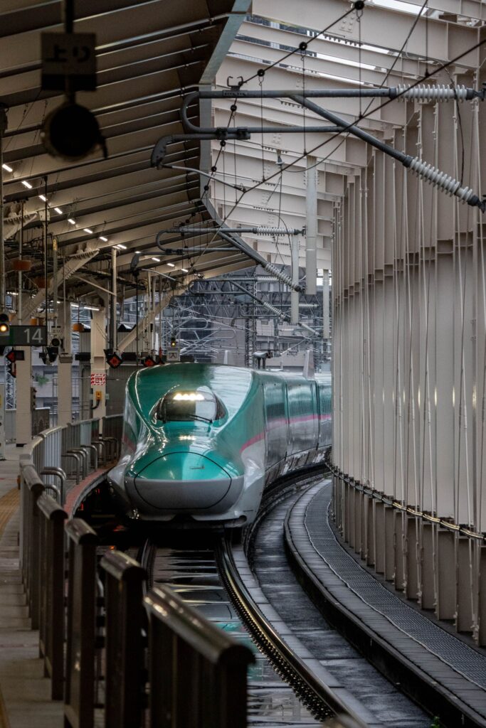 Green Shinkansen bullet train arriving at a Japanese railway station, highlighting Saitama's connection to Japan's high-speed rail network.