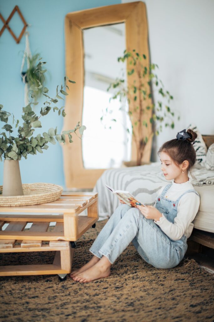 A young girl reading a book while sitting on a cozy carpet, showing how rugs can make floors more comfortable during winter.